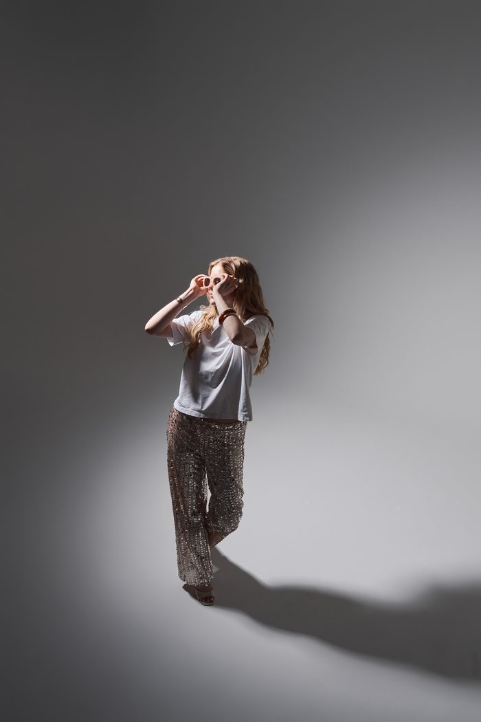 Mariat in sequin trousers holding her sunglasses