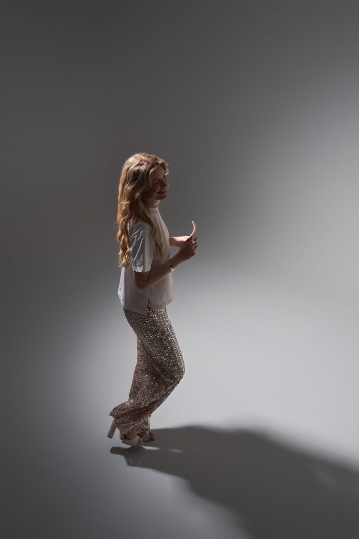 Mariat walking in sequin trousers, side view